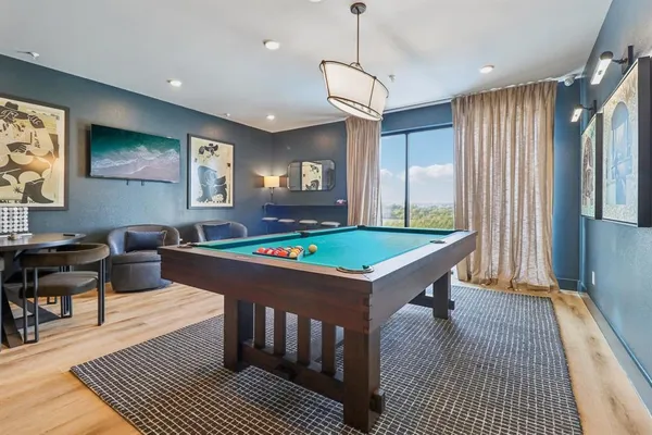 a room with furniture pool table flat screen tv and windows