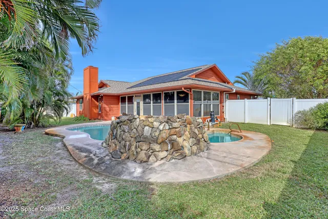 a view of a backyard with plants and a large tree