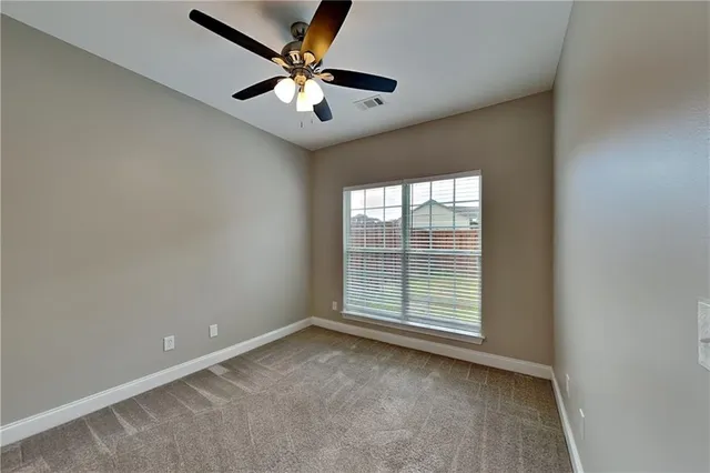 an empty room with a ceiling fan and window