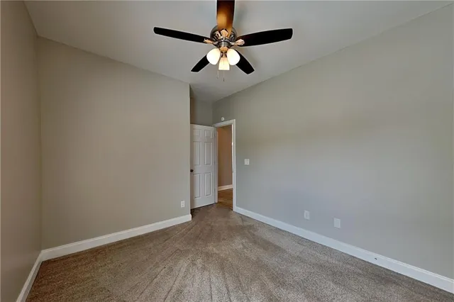an empty room with a ceiling fan and carpet