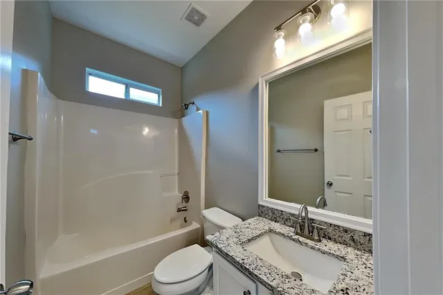 a bathroom with a granite countertop sink toilet and shower
