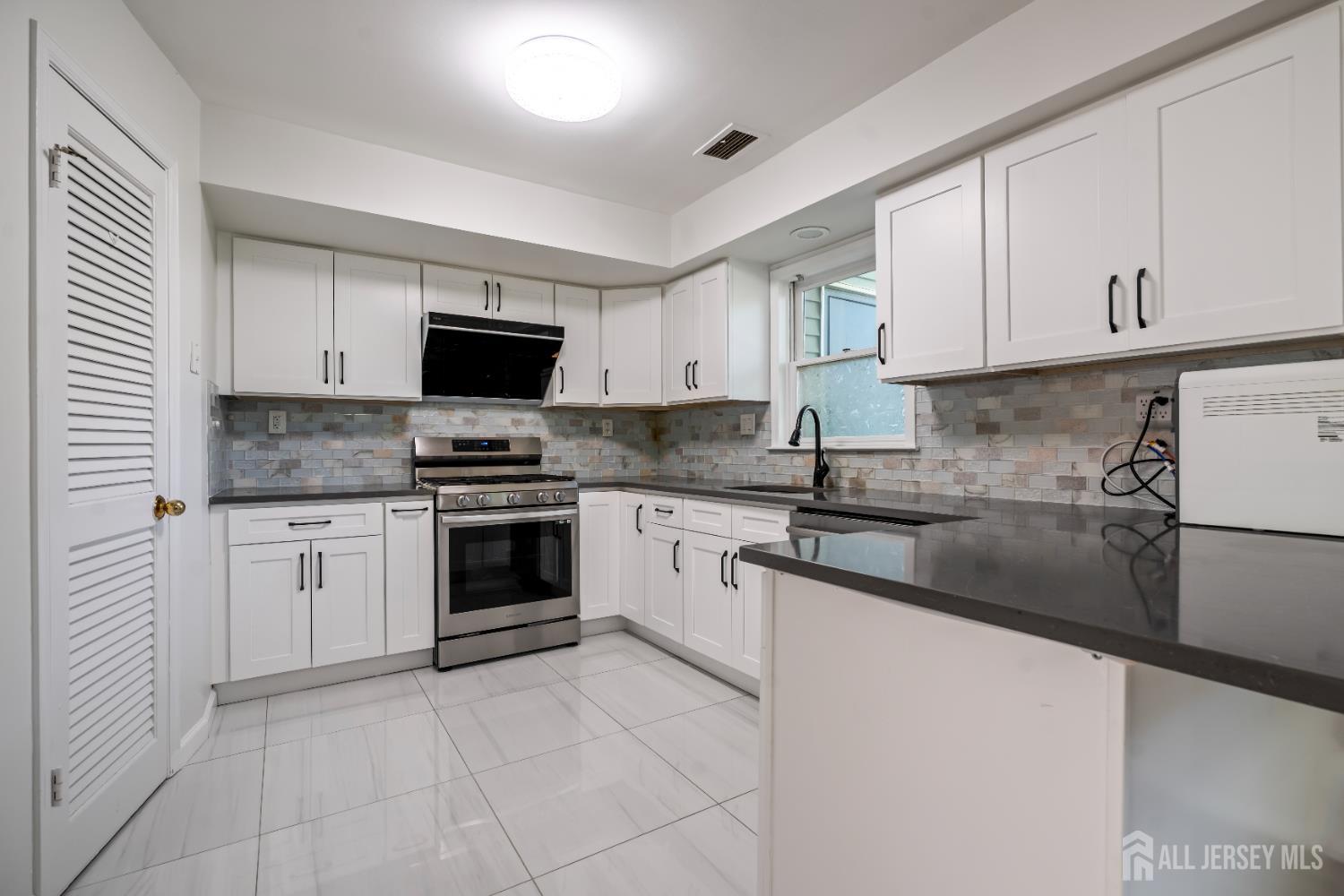 58 La Rue Lane East Brunswick, NJ 08816 - Photo 4 of 26 a kitchen with granite countertop white cabinets and stainless steel appliances