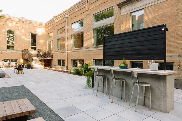 a patio with tables and chairs under an umbrella