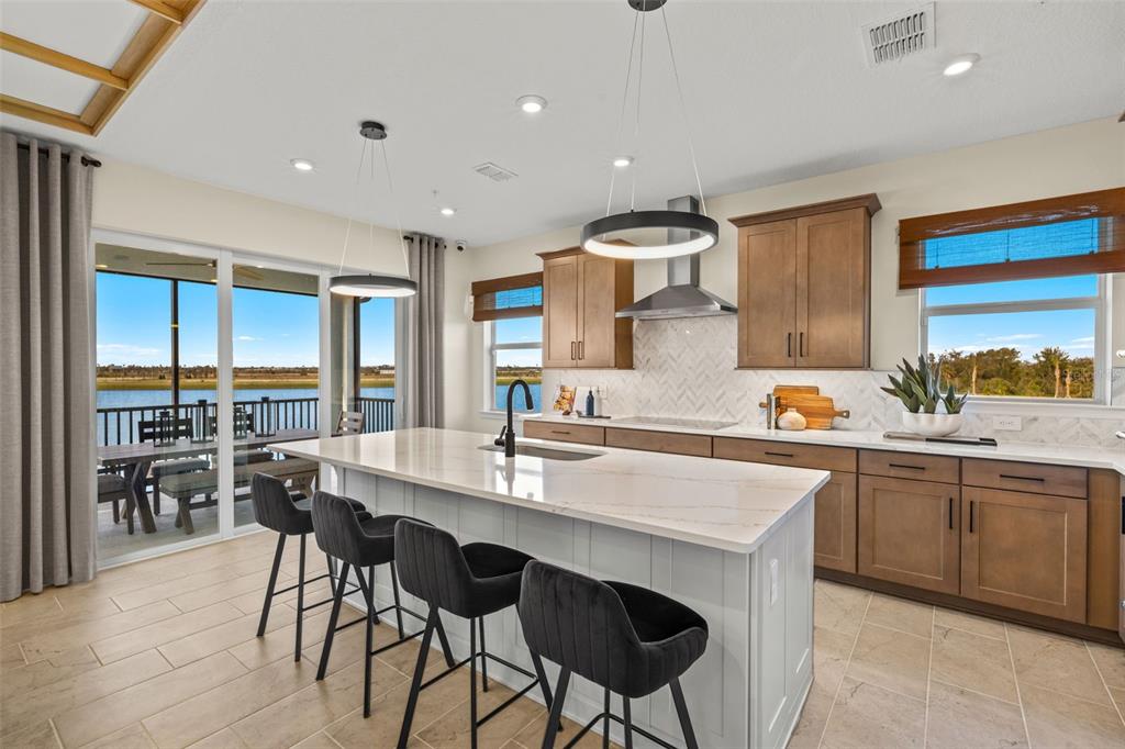 12829 Jade Empress Loop, Unit 201 Venice, FL 34293 - Photo 15 of 40 a kitchen with cabinets a sink dishwasher a island and chairs in it