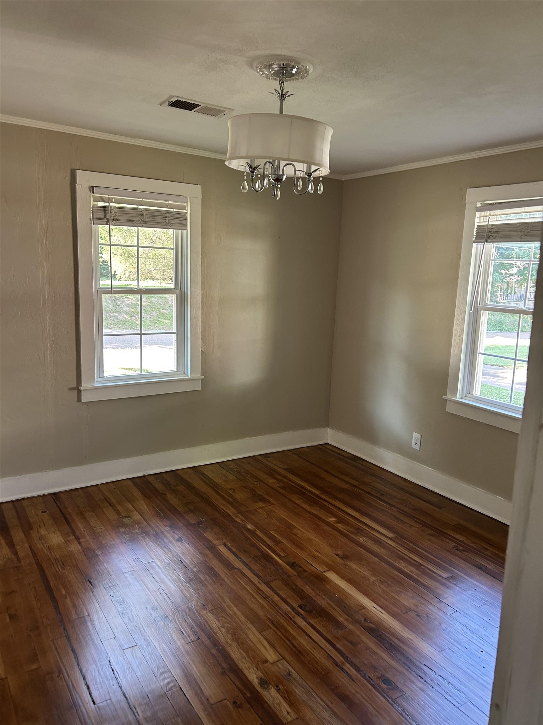 124 East Ripley Avenue Covington, TN 38019 - Photo 8 of 9 Unfurnished dining area with dark wood finished floors, crown molding, healthy amount of natural light, and a chandelier