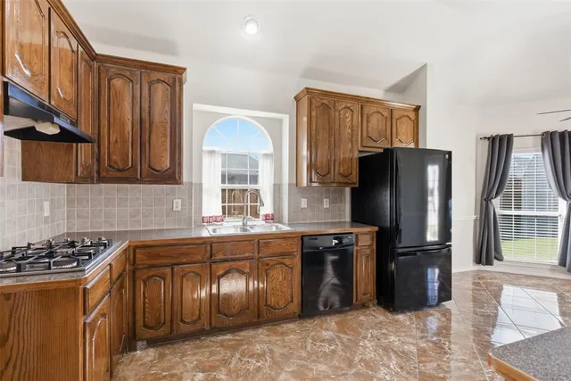 a kitchen with stainless steel appliances granite countertop a refrigerator a stove and a sink