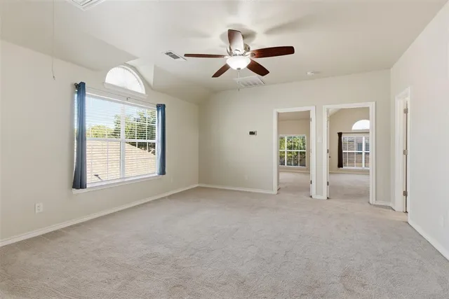 an empty room with windows and fan