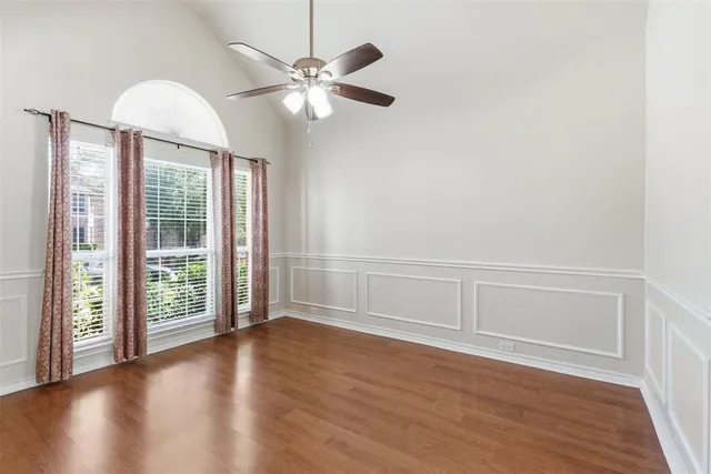 an empty room with wooden floor fan and windows