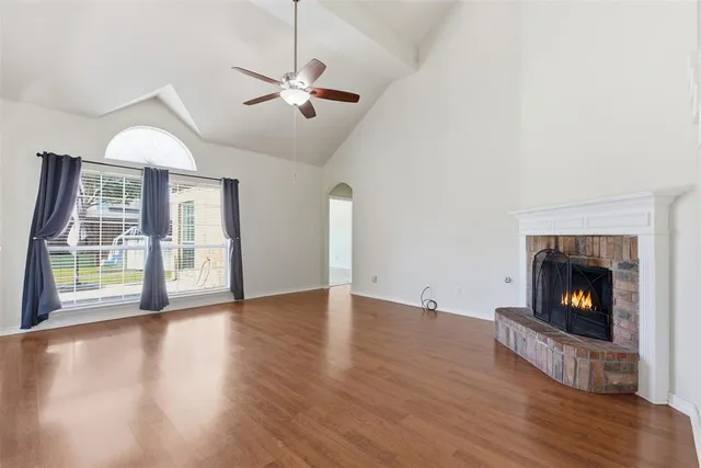 a view of an empty room with wooden floor fireplace and a window