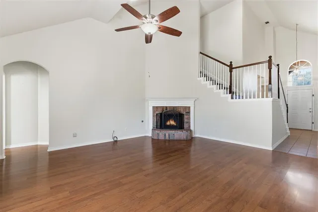 a view of an empty room with wooden floor and a fireplace