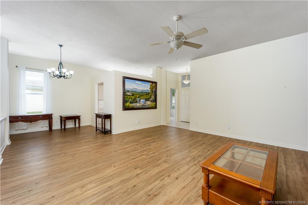 7199 Southeast Bitterroot Circle Hobe Sound, FL 33455 - Photo 13 of 28 an empty room with wooden floor chandelier fan and windows