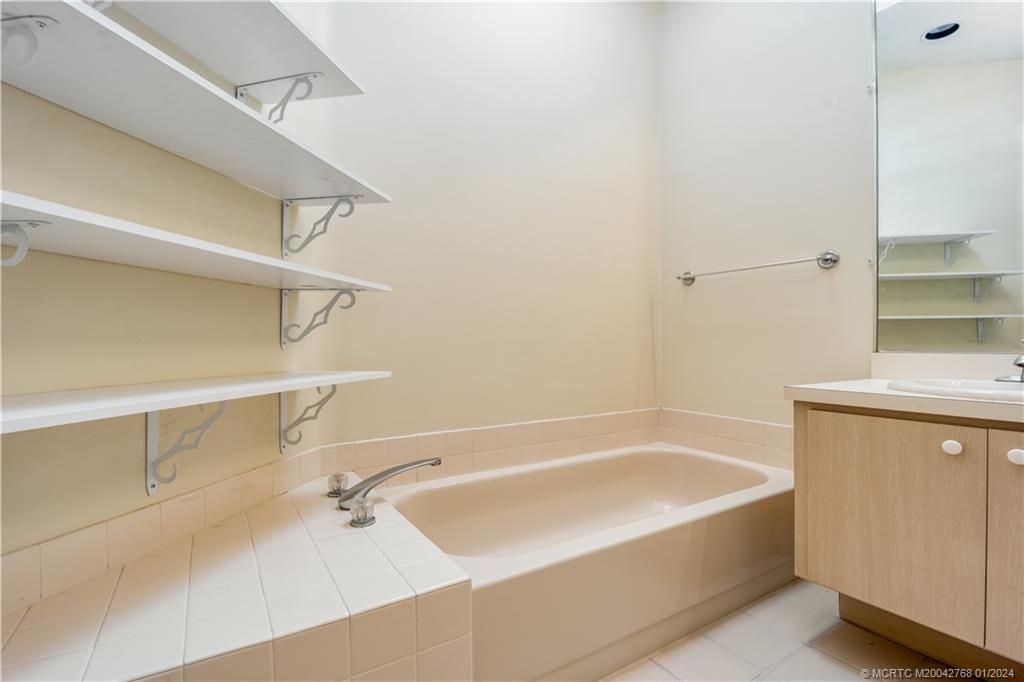 7199 Southeast Bitterroot Circle Hobe Sound, FL 33455 - Photo 20 of 28 a white bath tub sitting next to a white sink and vanity