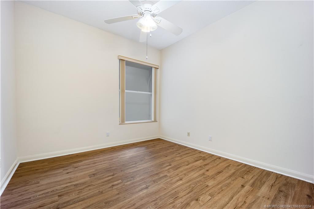 7199 Southeast Bitterroot Circle Hobe Sound, FL 33455 - Photo 24 of 28 an empty room with wooden floor fan and windows