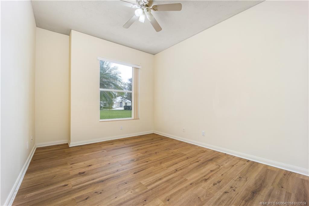 7199 Southeast Bitterroot Circle Hobe Sound, FL 33455 - Photo 26 of 28 an empty room with wooden floor fan and windows