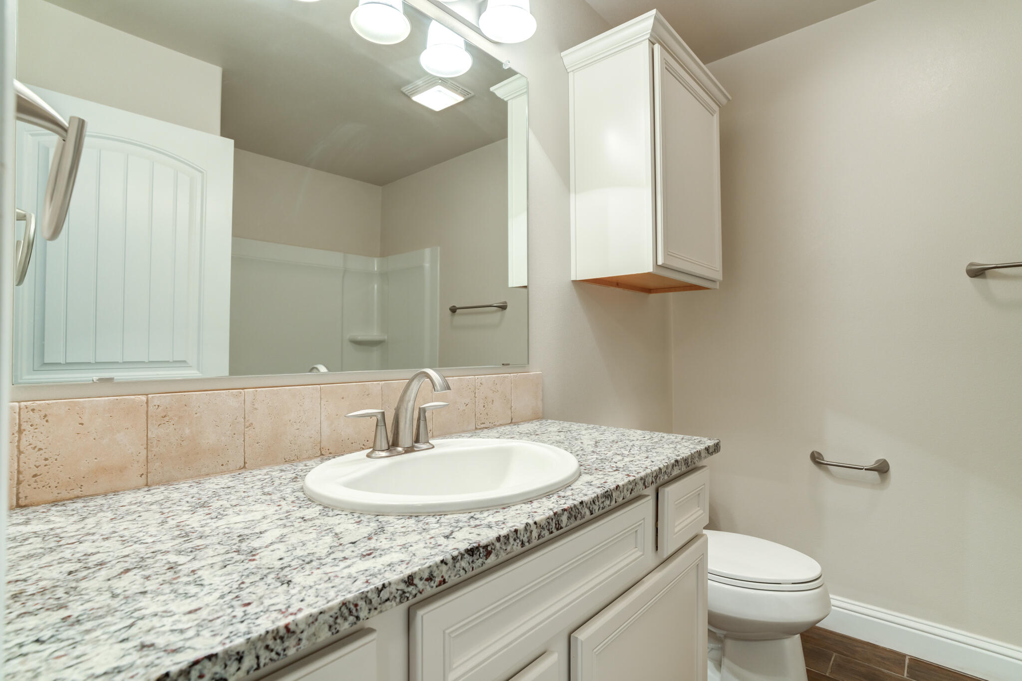 7535 103rd Street Lubbock, TX 79424 - Photo 31 of 35 a bathroom with a granite countertop sink a toilet and a mirror