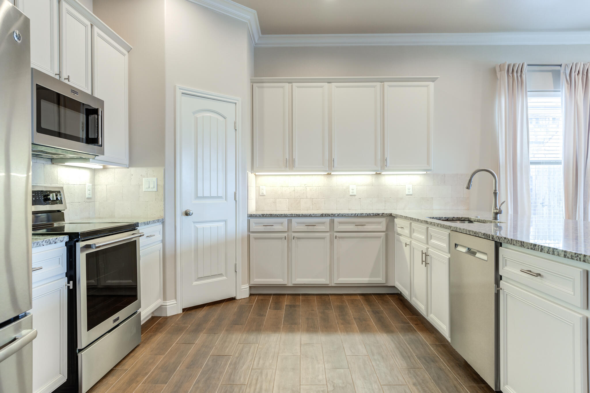 7535 103rd Street Lubbock, TX 79424 - Photo 6 of 35 a kitchen with granite countertop white cabinets stainless steel appliances and sink