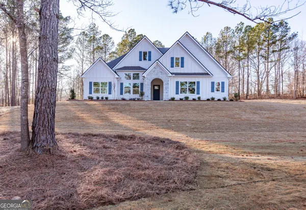 a front view of a house with a yard and large trees