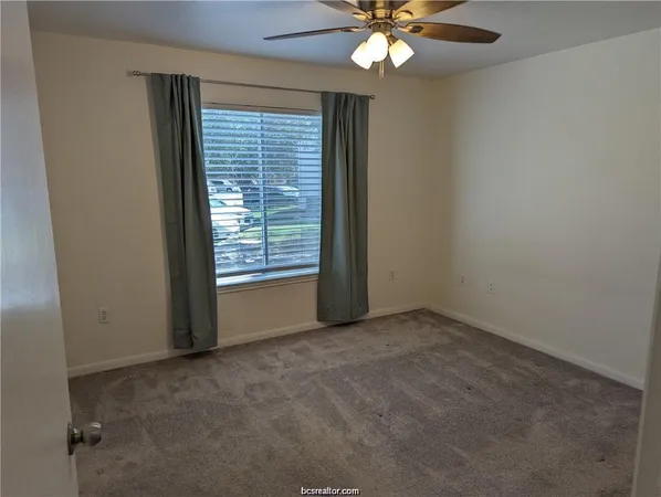 an empty room with windows and fan