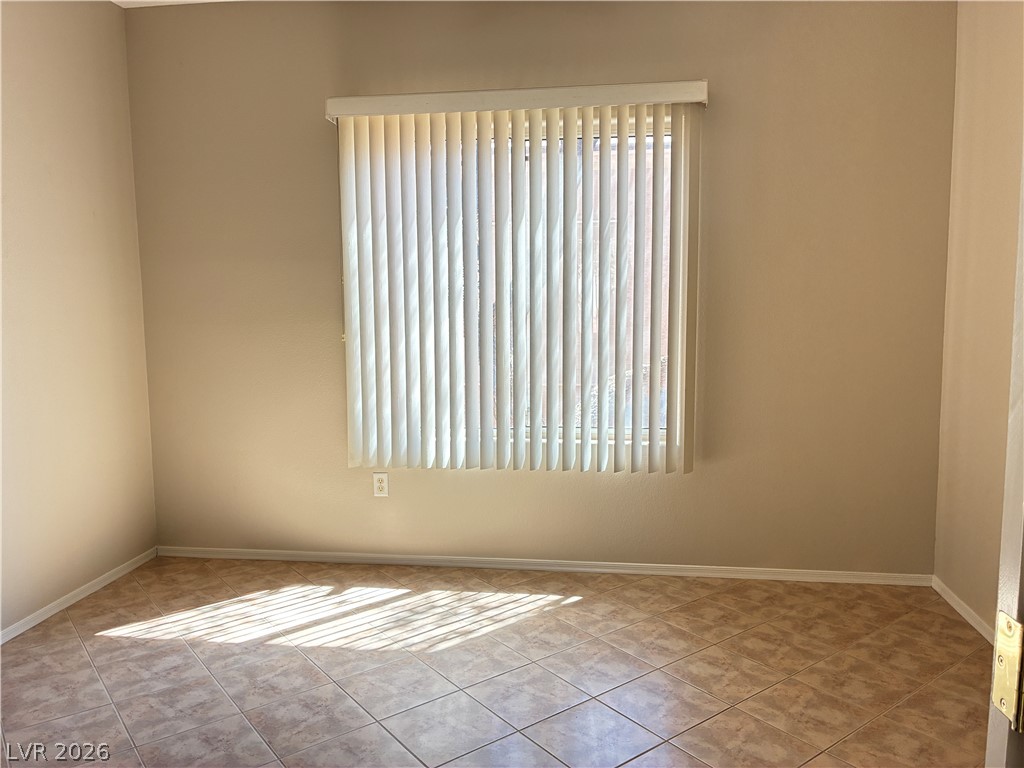 Sun-drenched interiors illuminate durable tile flooring and a window dressed with vertical blinds, offering both light and privacy.