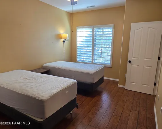 a bedroom with two beds and wooden floor