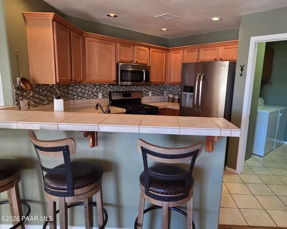 a kitchen with stainless steel appliances a dining table and chairs
