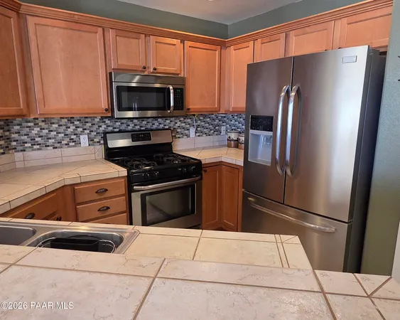 a kitchen with granite countertop a refrigerator and a microwave
