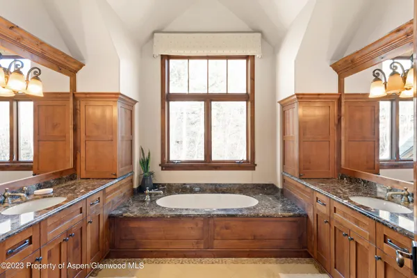a bathroom with a granite countertop tub sink and mirror
