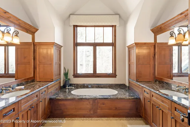 a bathroom with a granite countertop tub sink and mirror