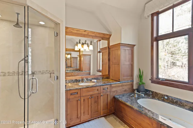 a bathroom with a granite countertop tub sink shower and mirror
