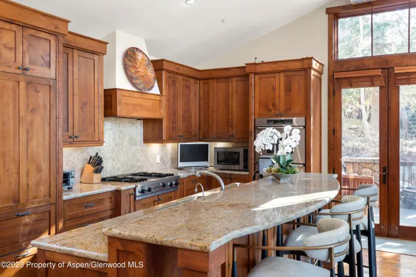 a kitchen with granite countertop a stove a sink dishwasher and a microwave with wooden floor