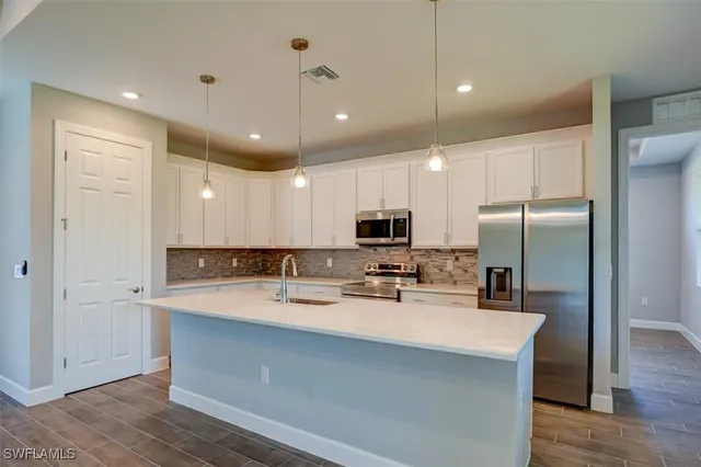 a kitchen with kitchen island a sink stainless steel appliances and cabinets