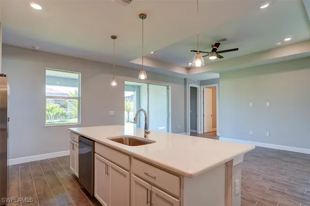 a kitchen with a sink a chandelier stainless steel appliances and cabinets