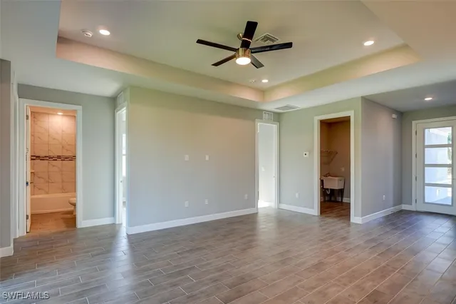 a view of an empty room with wooden floor and a ceiling fan
