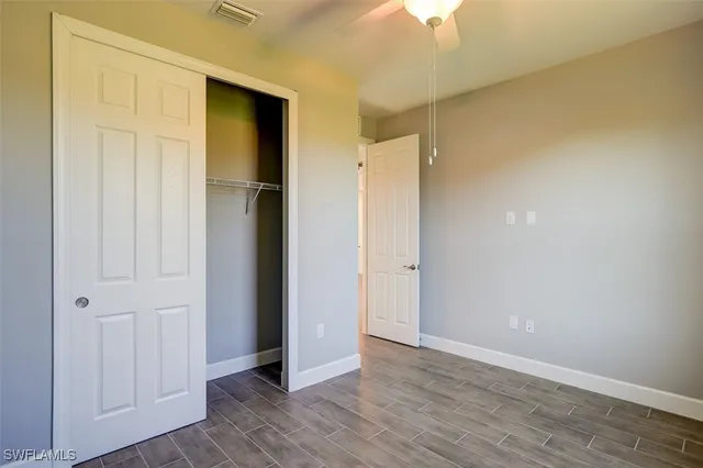 a view of an empty room with wooden floor and closet