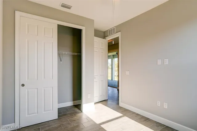 an empty room with wooden floor and closet area