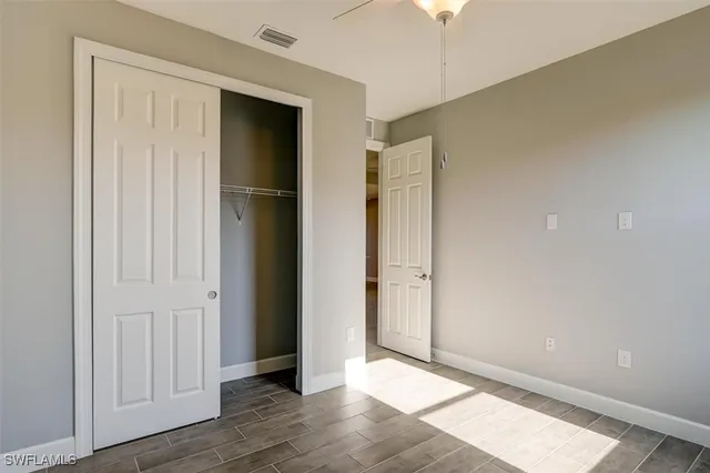 a view of an empty room with wooden floor and closet