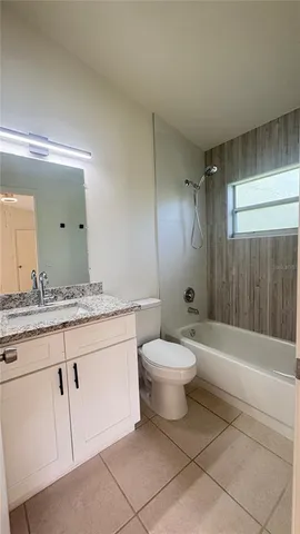 a bathroom with a granite countertop sink a toilet mirror and bathtub