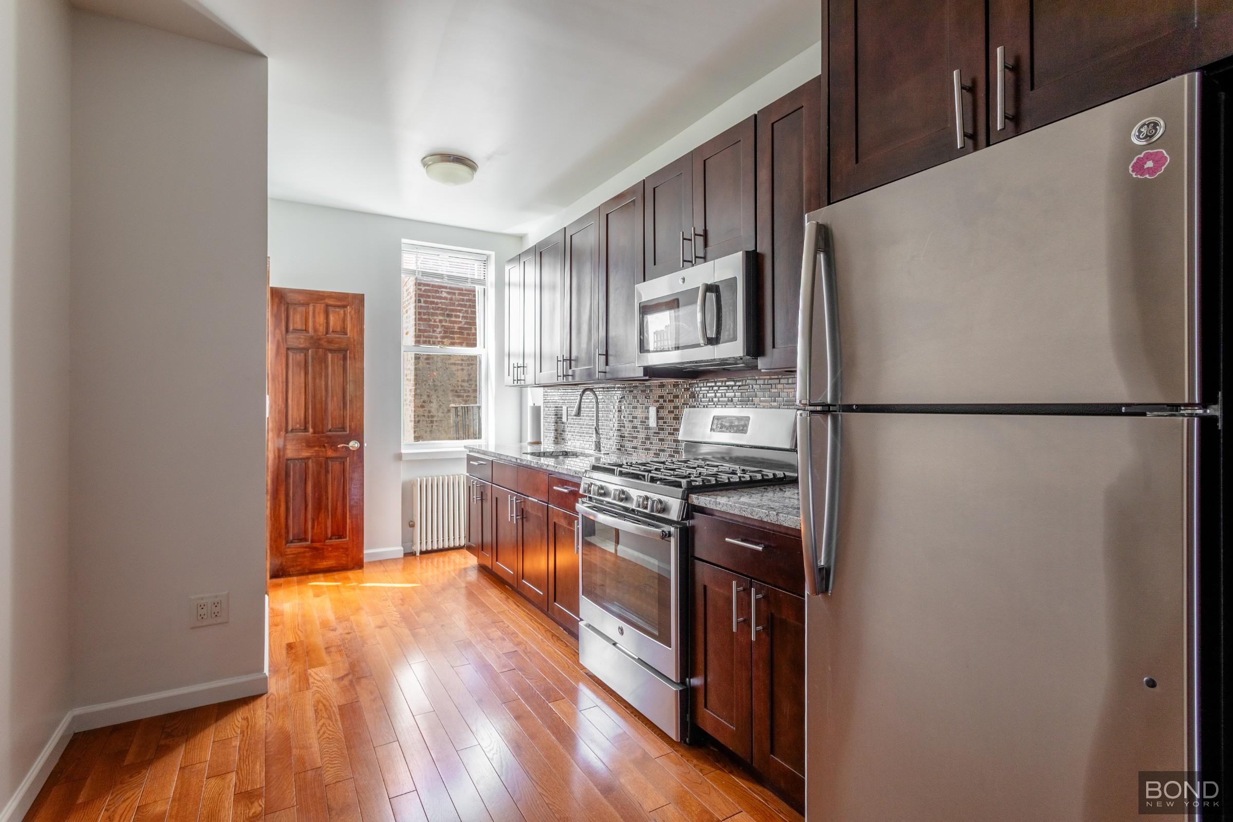 a kitchen with stainless steel appliances granite countertop a refrigerator a stove a sink dishwasher and a refrigerator with wooden floor