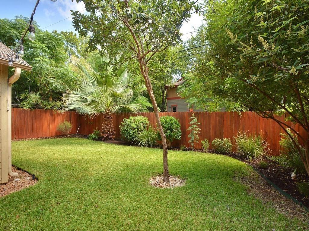 610 West N Loop Boulevard Austin, TX 78751 - Photo 26 of 29 The property features a well-maintained lawn, a wooden fence, and mature trees providing shade and privacy