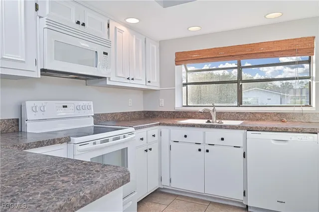 a kitchen with granite countertop white cabinets and a window