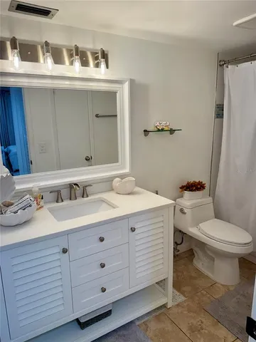 a bathroom with a granite countertop toilet sink and mirror
