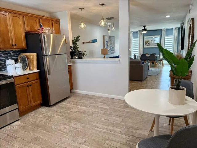 a kitchen with stainless steel appliances granite countertop a refrigerator dining table and chairs