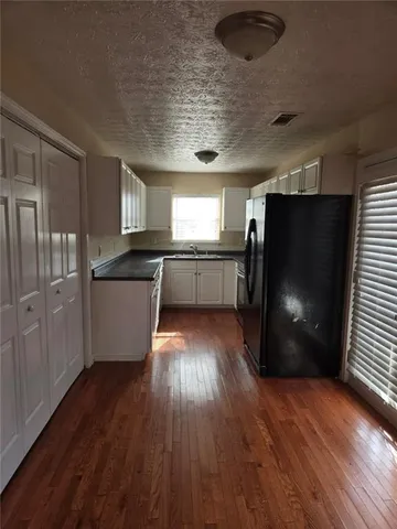 a kitchen with stainless steel appliances granite countertop a refrigerator a sink dishwasher a stove and white countertops with wooden floor