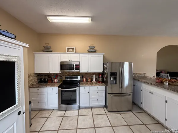 a kitchen with granite countertop a stove sink and refrigerator