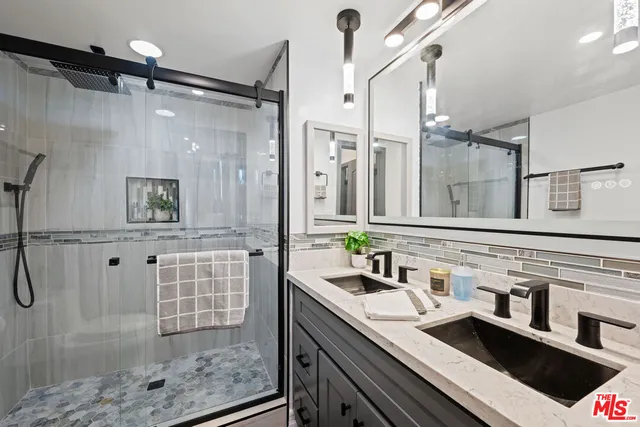 a bathroom with a granite countertop sink a mirror a bathtub and shower