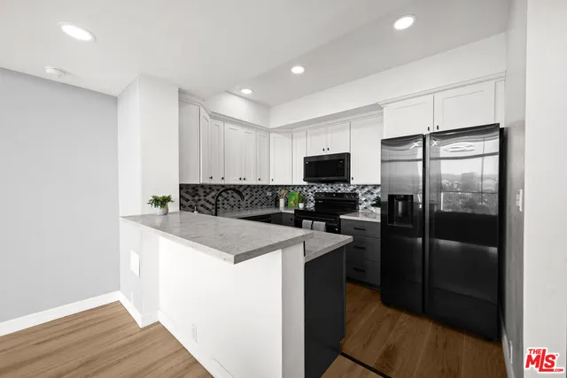 a kitchen with a refrigerator a microwave and white cabinets