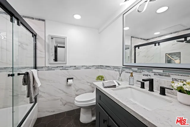 a bathroom with a granite countertop sink mirror and toilet