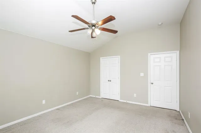 an empty room with a chandelier fan and a table