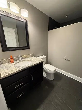a bathroom with a granite countertop sink a toilet and a mirror