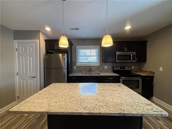 a kitchen with kitchen island granite countertop wooden cabinets a refrigerator and a sink